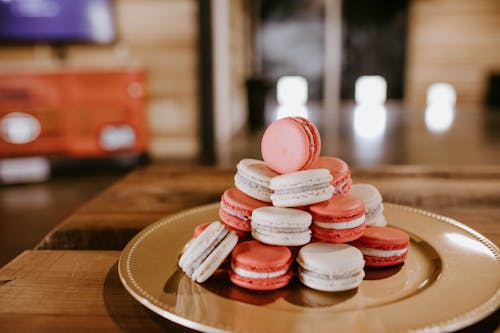 Delicious sweet macaroons with cream filling stacked on plate for dessert on wooden table
