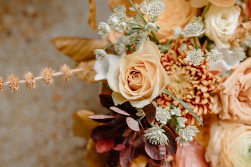 Top view of blossoming bouquet of fresh roses and chrysanthemum with branches and foliage placed on blurred background during holiday celebration