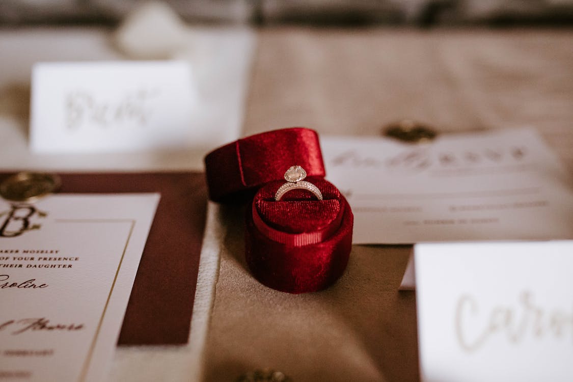 Free Red box with golden ring placed on table with invitation cards Stock Photo