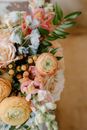 From above of fragrant bouquet with fresh peach buttercups composed with roses and green leaves in daylight