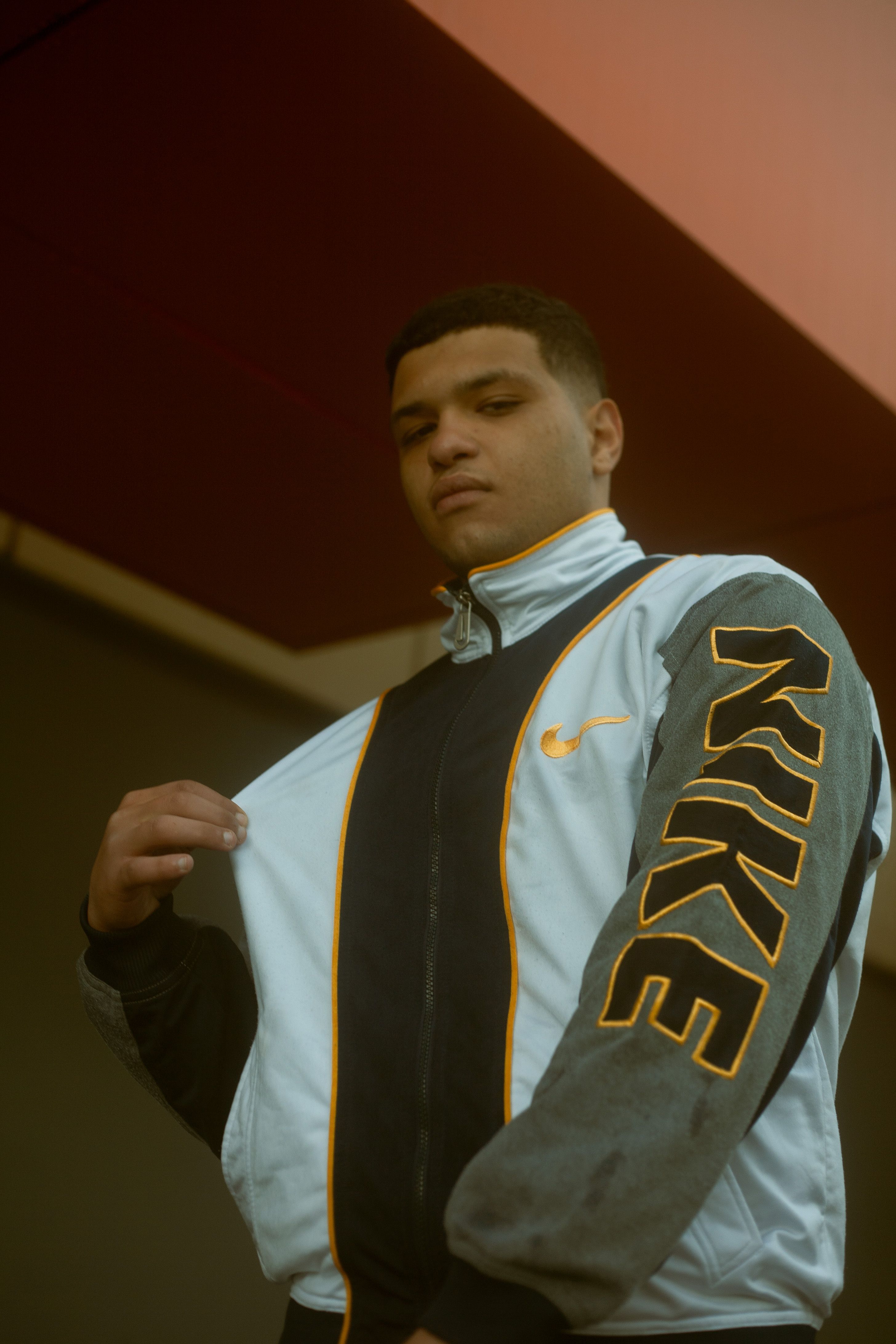Fashion portrait of a teenager in a Nike jacket, posing confidently on a sunny day in Morocco.