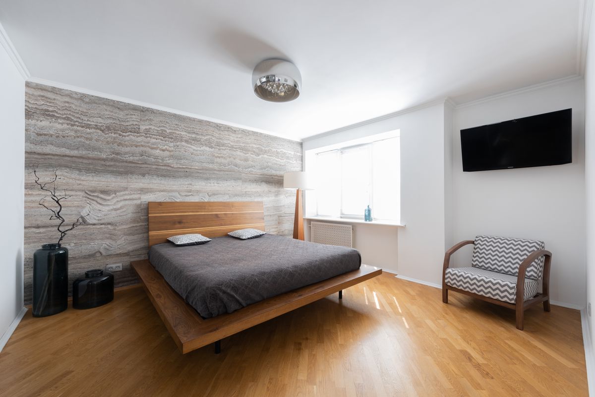 Wood-textured wallpaper accent wall behind a modern platform bed.