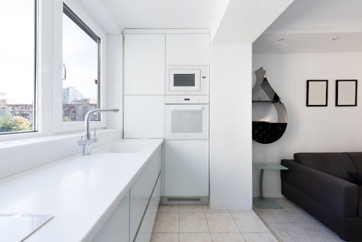 A bright and contemporary kitchen area with sleek white cabinets and integrated appliances.