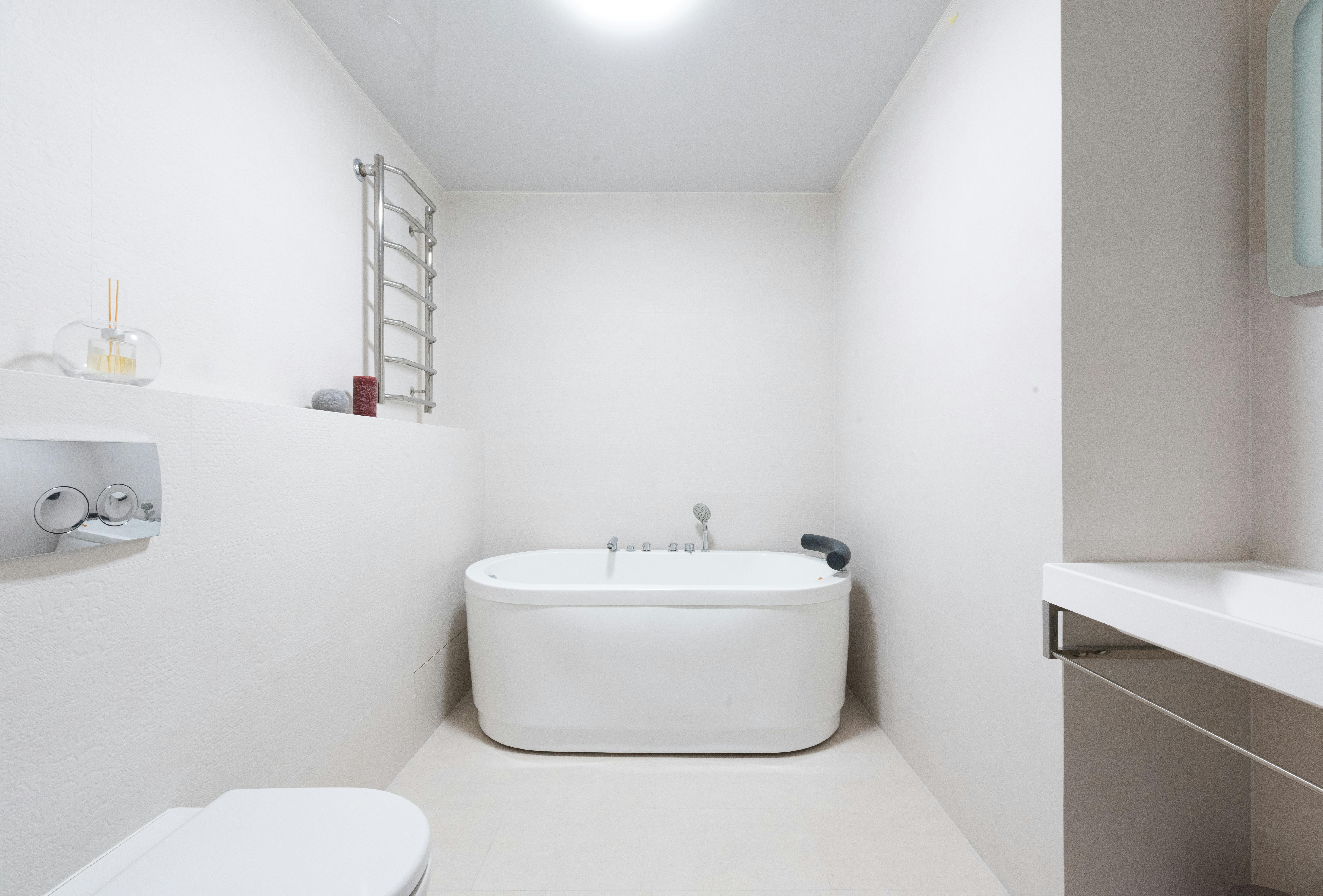 interior of light bathroom with toilet and sink near bathtub