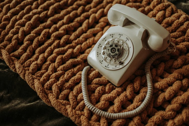 White Corded Telephone On Brown Textile