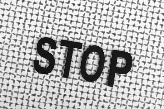Black wooden letters spelling 'STOP' on a black and white grid background.