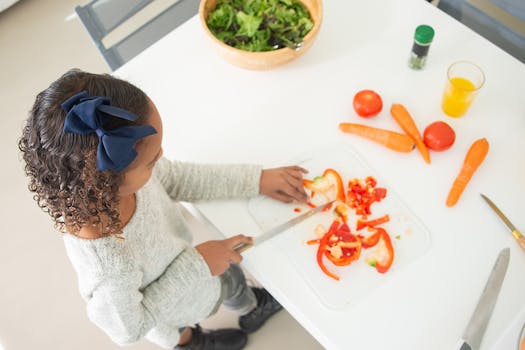 A child slicing peppers for a fresh salad in a bright kitchen setting.