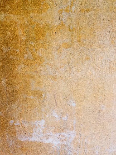 Close-up of a weathered yellow wall featuring textured concrete in Phú Quốc, Vietnam.