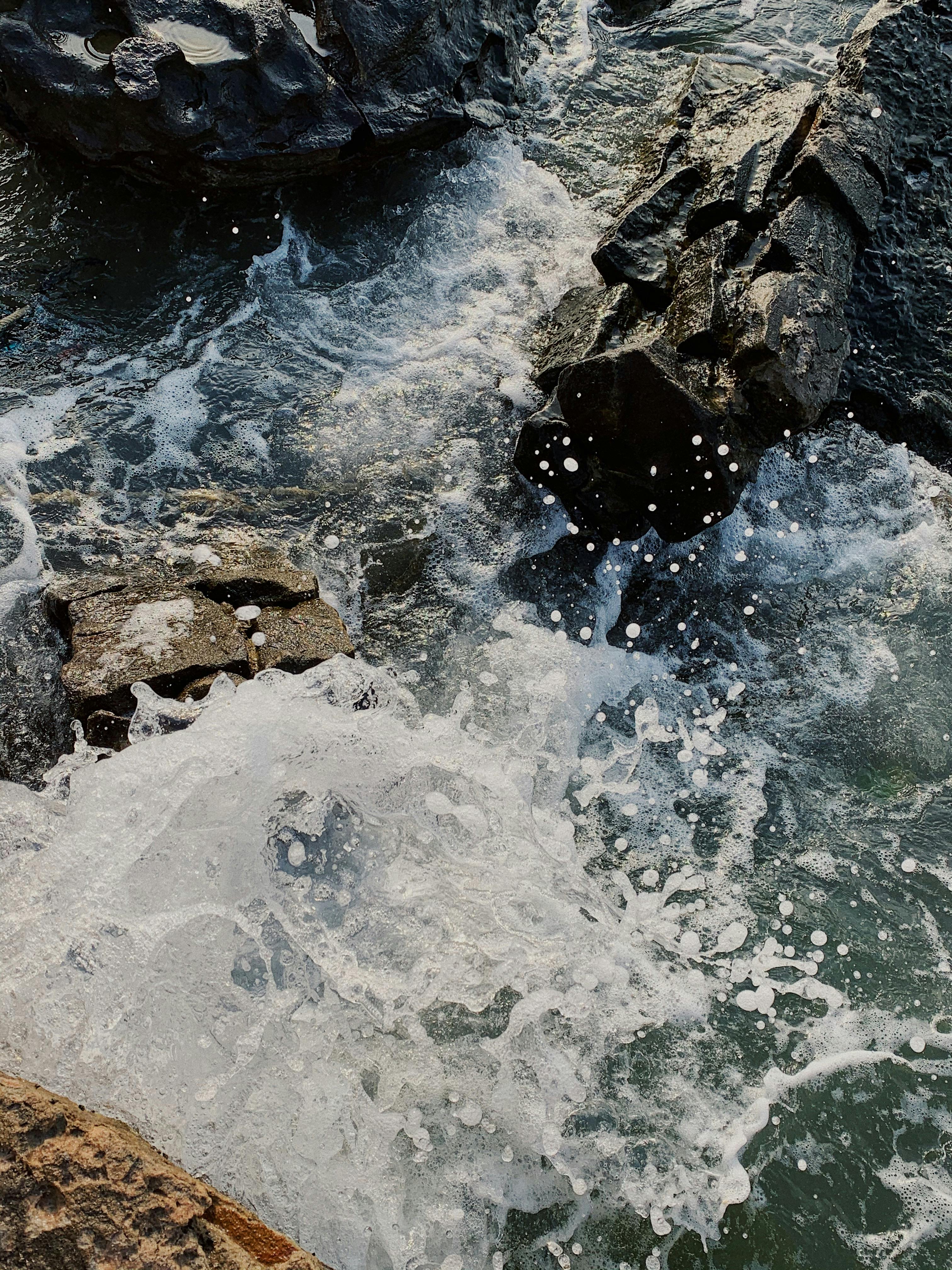 Capture of ocean waves splashing against rugged rocks in Phú Quốc, Vietnam, showcasing nature's power.