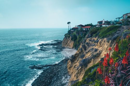 Free Stunning view of Laguna Beach cliffs with ocean waves and coastal homes under a clear sky. Stock Photo