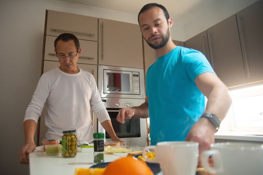 Two men enjoy preparing breakfast together in a modern kitchen setting, showcasing togetherness and culinary joy.