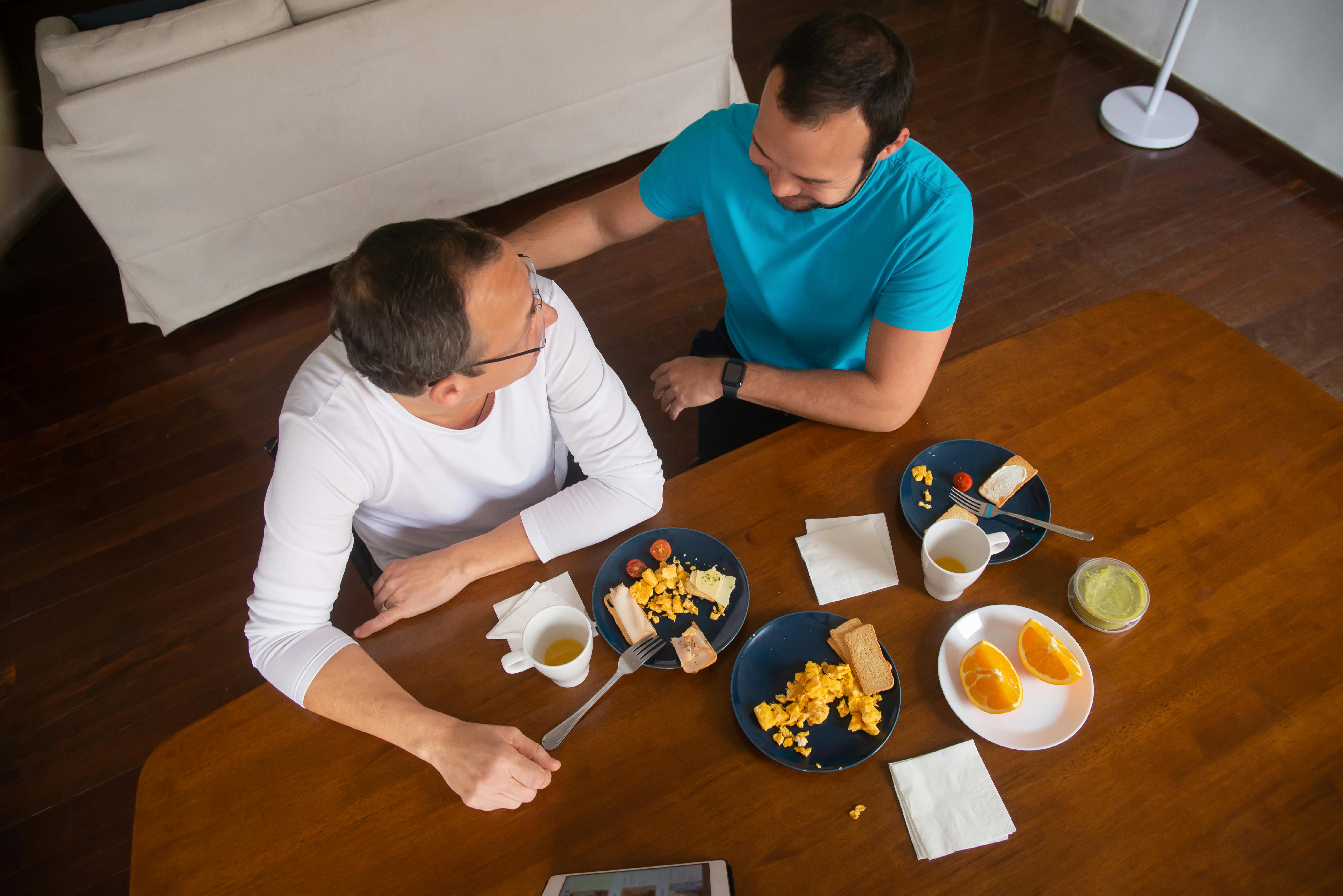 a same sex couple having conversation near the table with foods