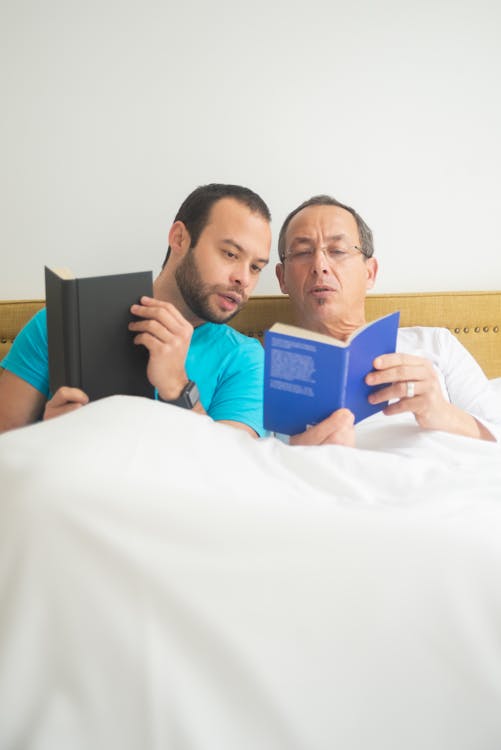 Free Men Reading Books while in Bed Stock Photo