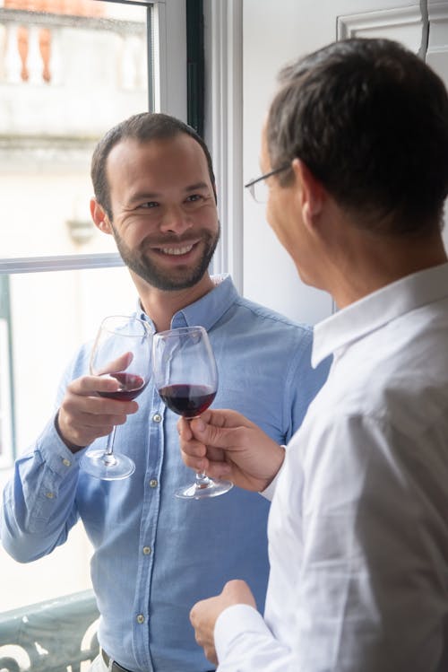 Free Двое мужчин смотрят друг на друга Звон бокалов с красным вином Stock Photo