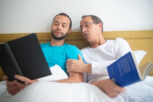 Dois Homens Reclinados Na Cama Lendo Livros