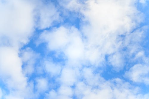 Low angle of bright blue sky with floating white fluffy cumulus clouds as abstract background