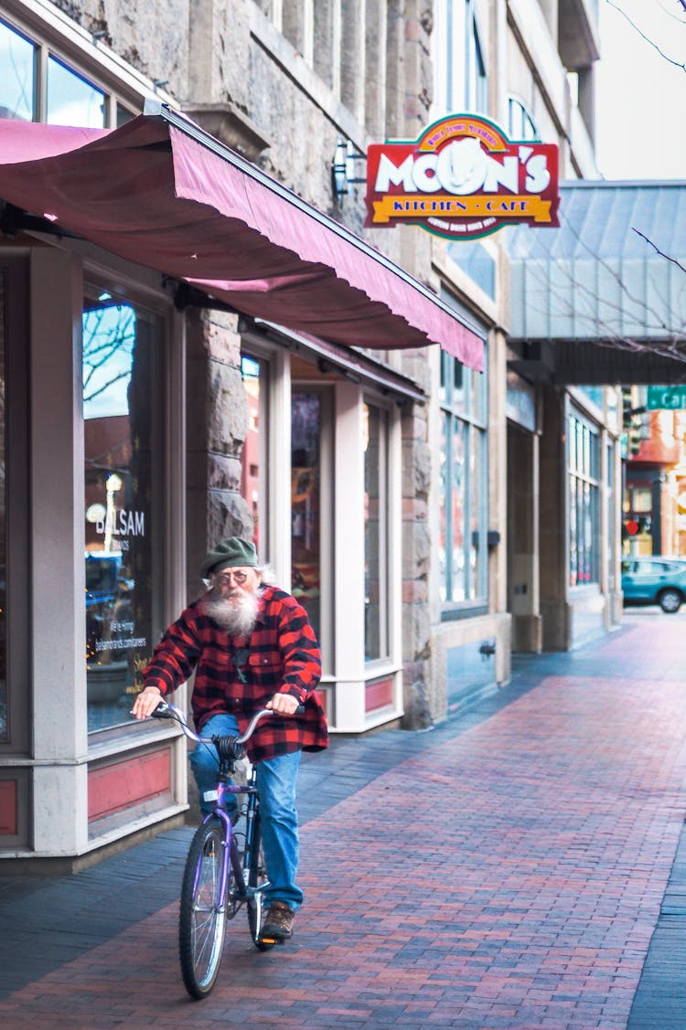 Elderly Male Hipster Riding Bicycle On City Street