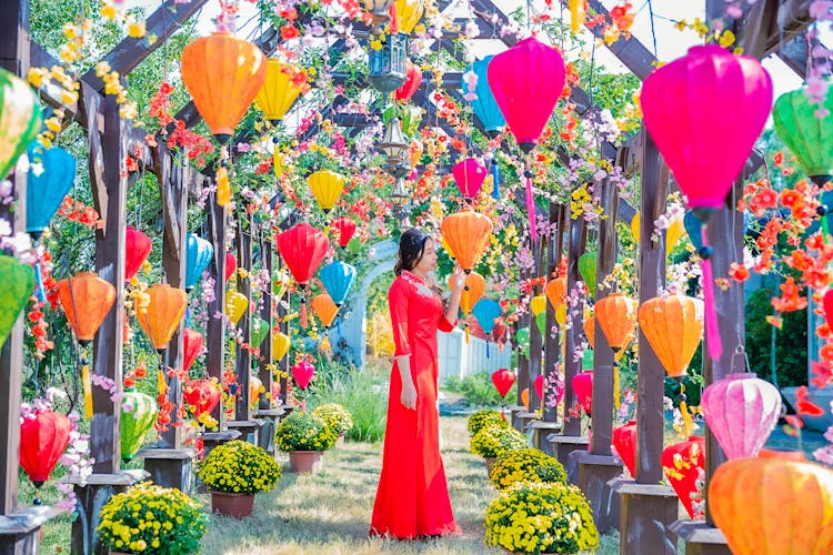 Woman In Red Dress Standing In The Garden With Colorful Lanterns