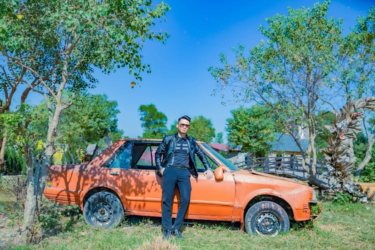 Man In Black Leather Jacket Standing Beside An Abandoned Car