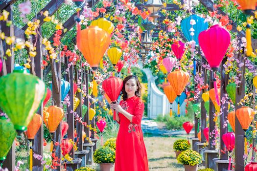 A woman in traditional attire amidst colorful lanterns and florals, exuding a festive spring vibe.