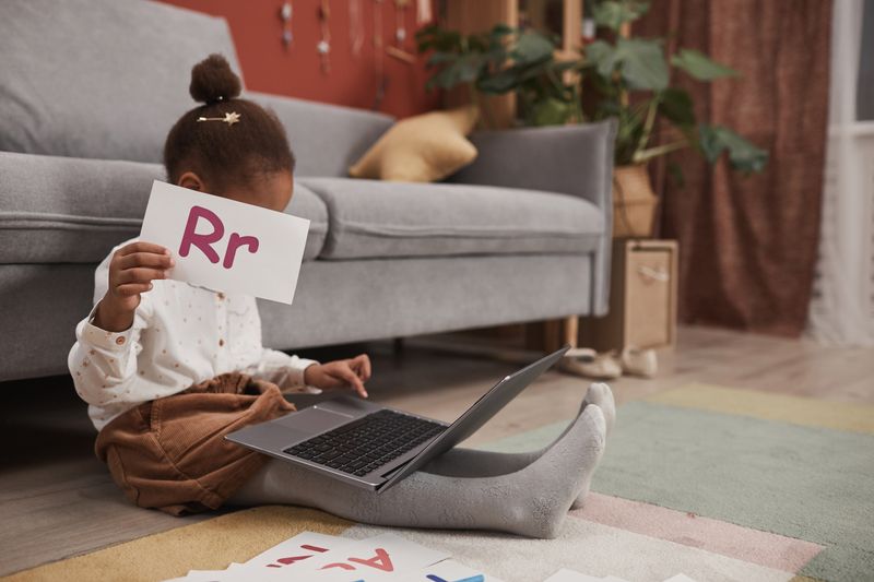 Child learning with alphabet cards and laptop at home