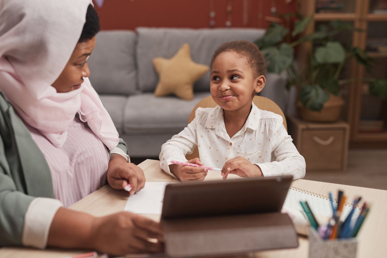 Mother and school-aged daughter smiling while learning together