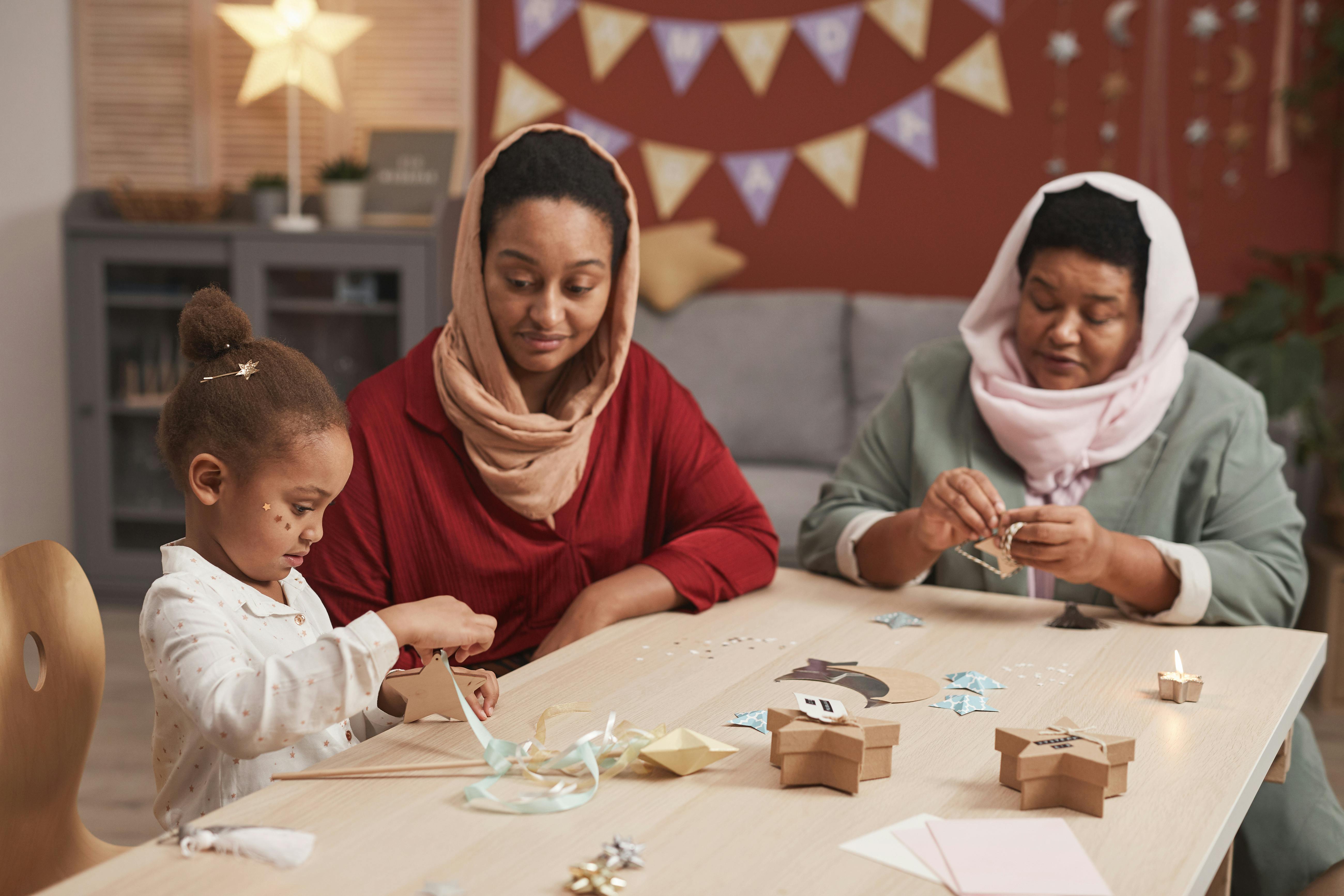 grandma and mother preparing paper decorations with little girl