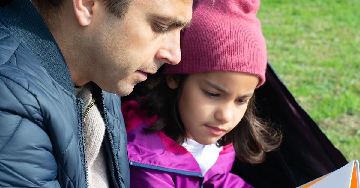 Father and Daughter Reading a Book while Sitting Inside the Tent