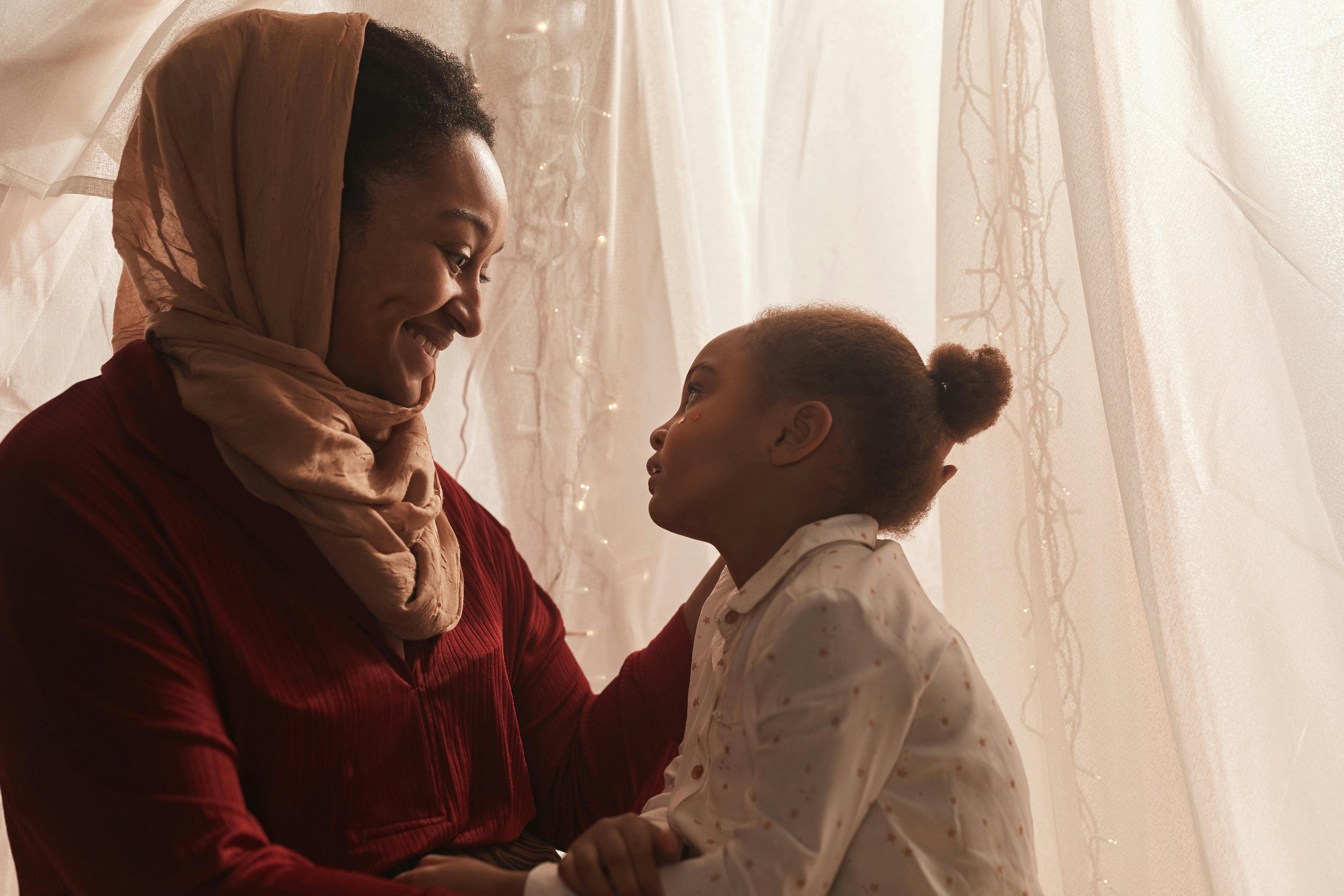 A heartwarming scene of a mother and daughter expressing affection inside a cozy tent.
