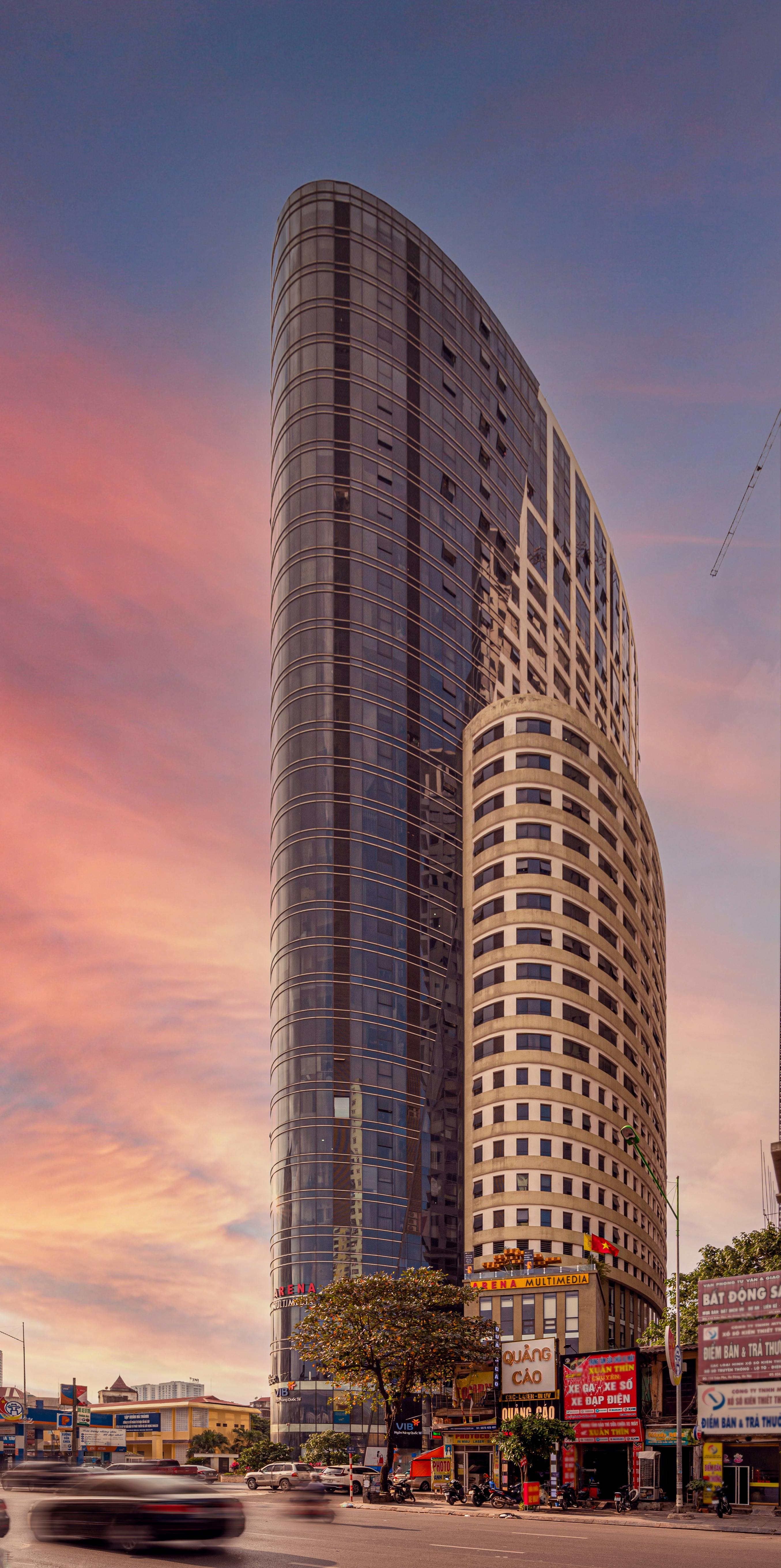 A sleek modern skyscraper stands tall against a vibrant sunset sky, showcasing urban architecture.