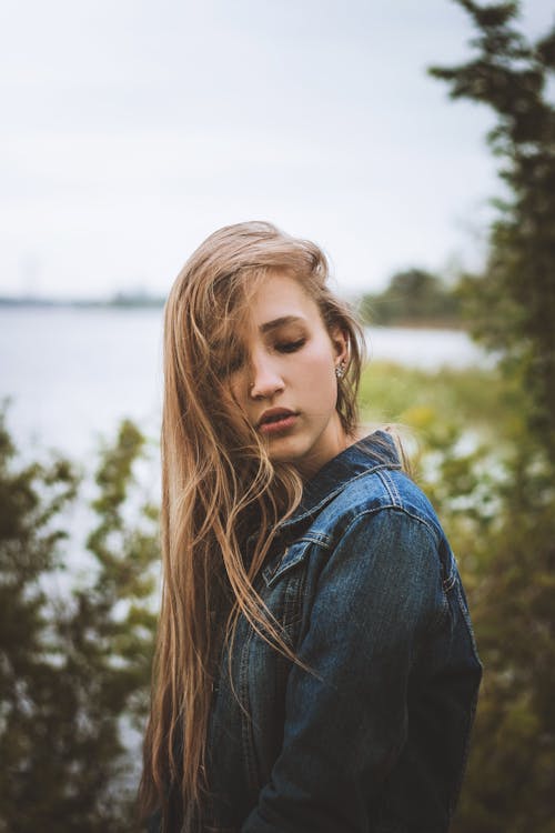 Dreamy woman near lake with bushes