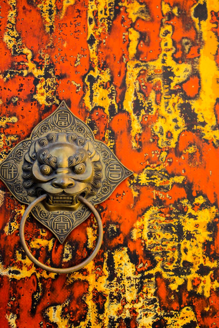 A Red And Yellow Door With Ornate Knocker