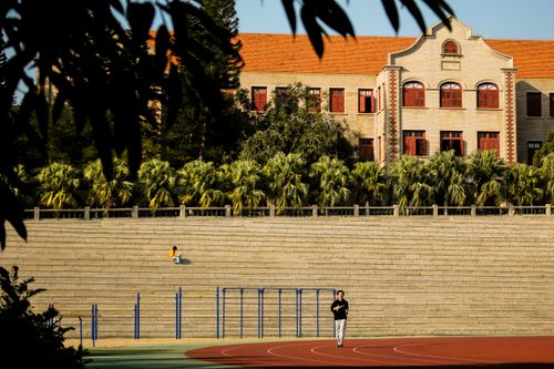 Free Man jogging on a track by historic university, sunny day. Stock Photo
