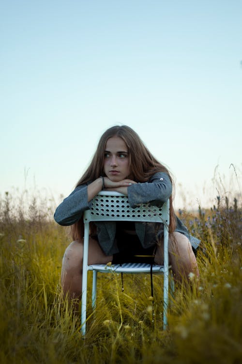 A Young Woman Posing on a Chair in a Field