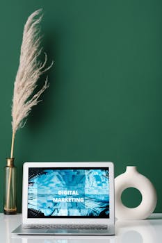 Laptop displaying digital marketing on screen with decorative items on a desk.