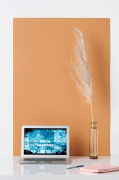 Stylish minimalist workspace with laptop showing digital marketing, vase with pampas grass, and copy space.