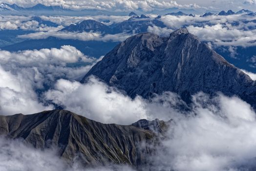 A breathtaking aerial view of jagged mountain peaks surrounded by clouds, capturing nature's beauty.