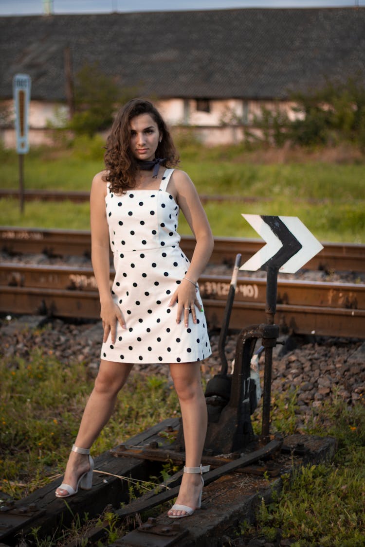 A Woman In White Polka Dot Dress Standing Near The Railroad Track