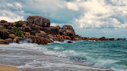 Brown and Green Rock Formation by the Seashore