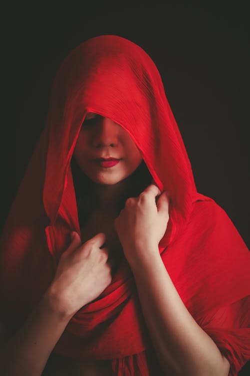 Photo of a Woman Covering Her Face with a Red Scarf
