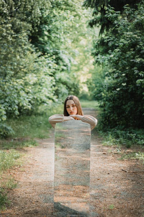 Woman Holding a Mirror on a Path in Forest 