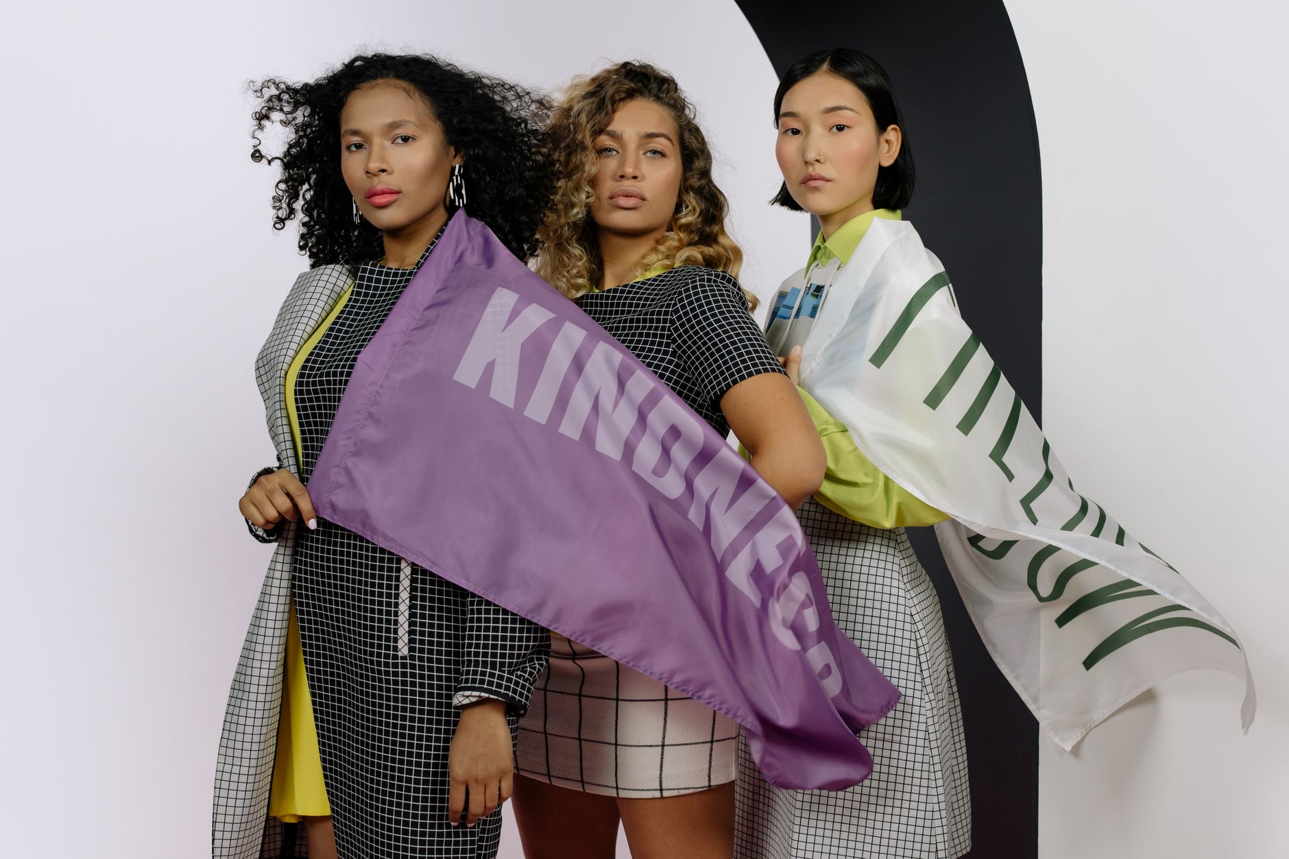 Elevate Women Authors and Coaches with Life-Changing Sites (Plus a Freebie to Start Your Empowered Launch) Three women stand united, celebrating diversity with kindness-themed flags.