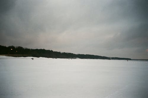 Snow Covered Land Under Gray Clouds