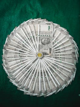 Top view of Indian Rupee notes arranged in a circular pattern on a green surface.