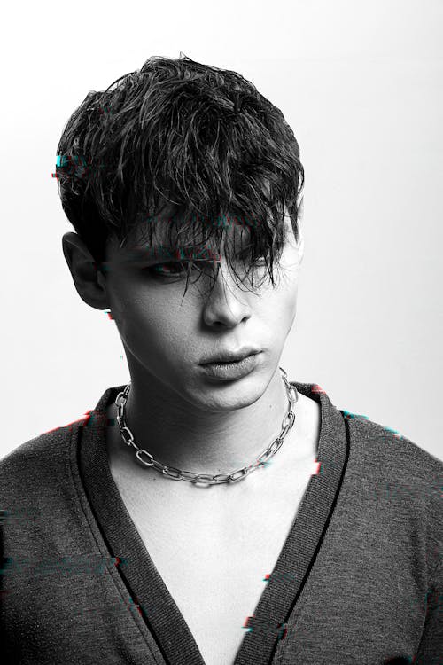 Black and white of young trendy man with modern haircut and chain looking away
