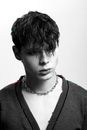Black and white of young trendy man with modern haircut and chain looking away