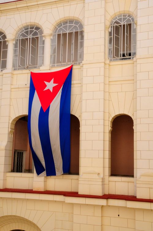 Free Cuban flag draped over a historic building façade. Perfect for architecture and travel themes. Stock Photo