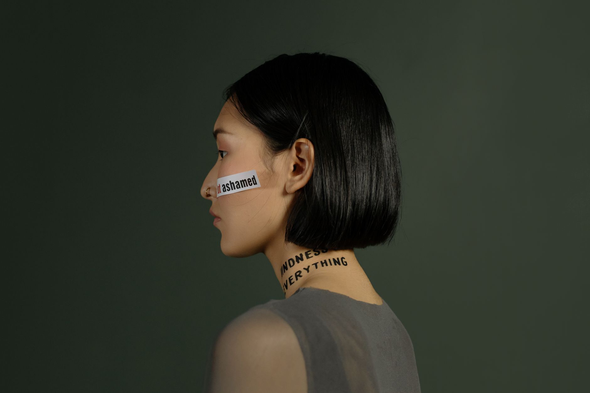 Side view of a young woman with words on her face and neck, symbolizing freedom and choice.