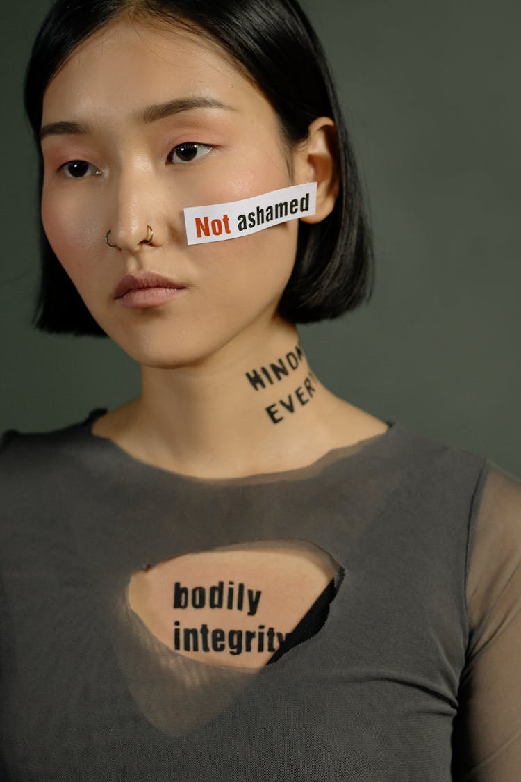 Young Woman Standing With Slogan Quotes On Her Face And Neck