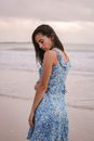 Side view of young reflective female traveler with closed eyes on sandy sea shore in evening